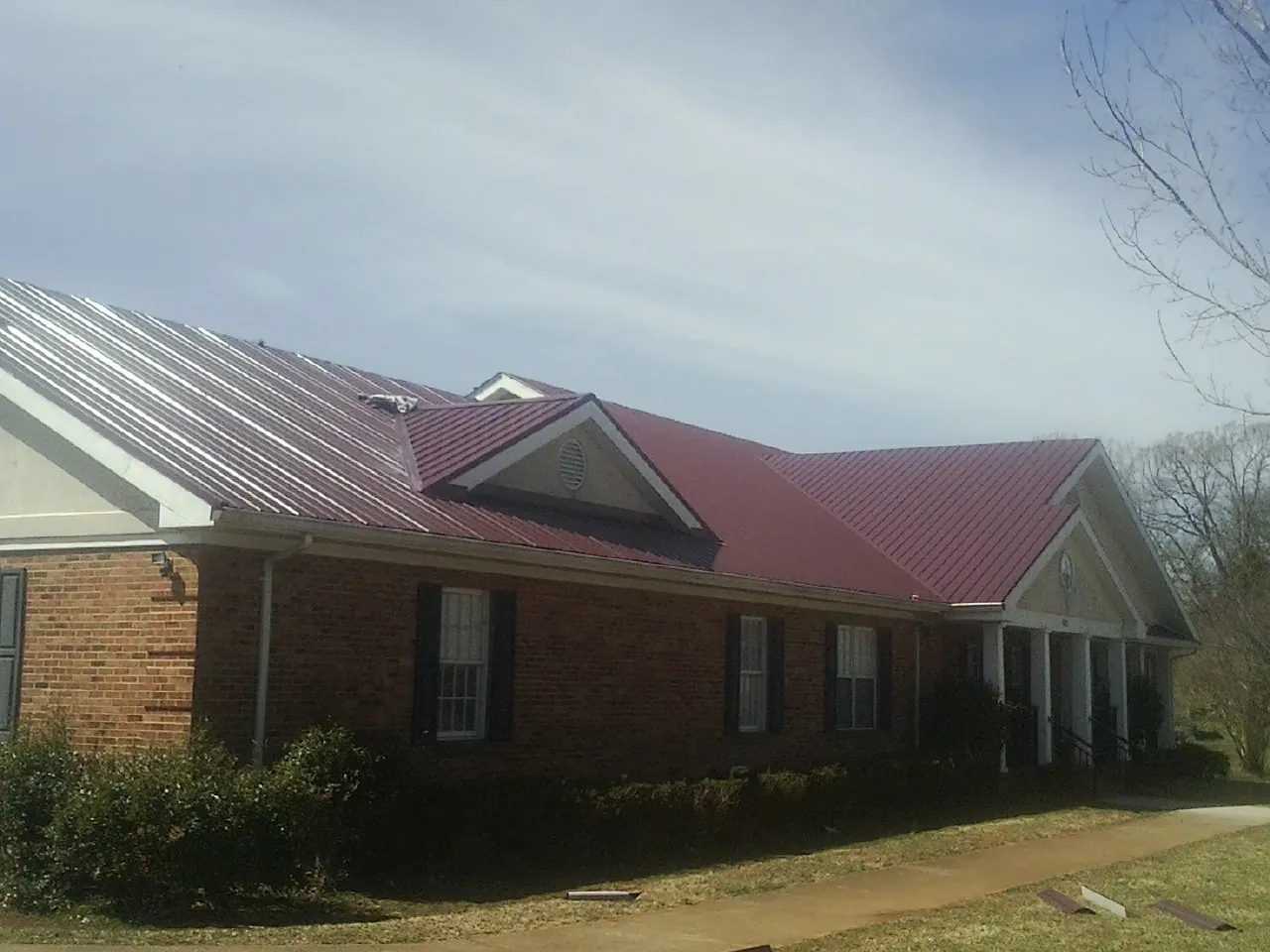 Red metal roof with gabled entries on a long brick building in Fayette